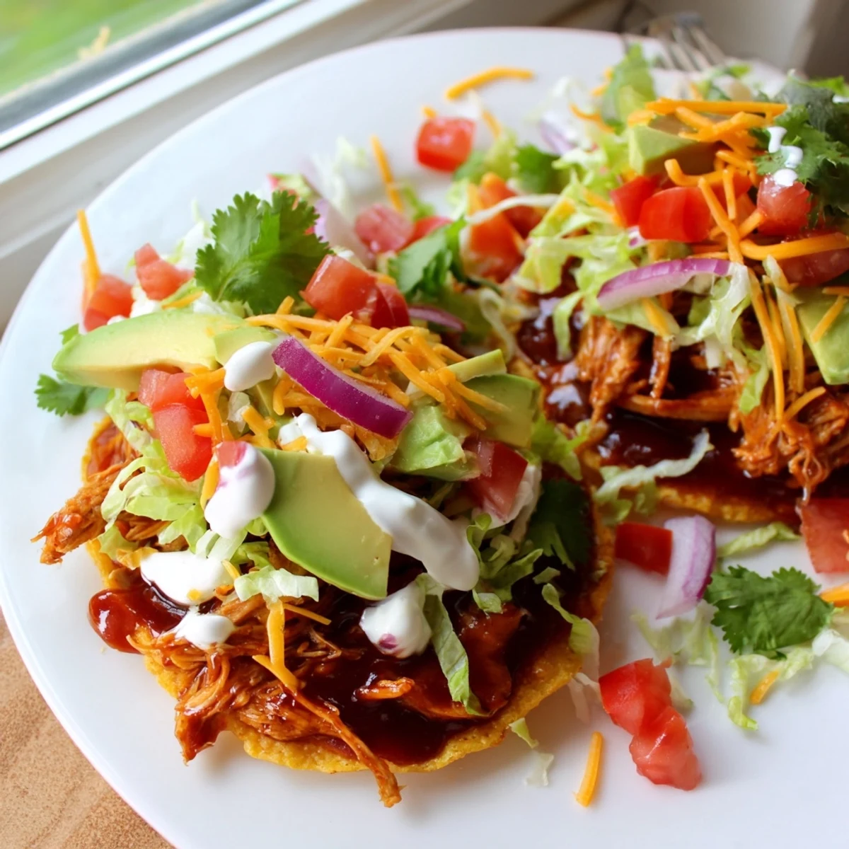Crispy sweet smoky BBQ chicken tostadas piled high with fresh lettuce and creamy avocado