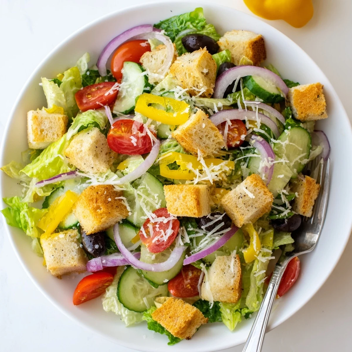Creamy Parmesan-topped Olive Garden Salad featuring pepperoncini, black olives, and crisp romaine lettuce