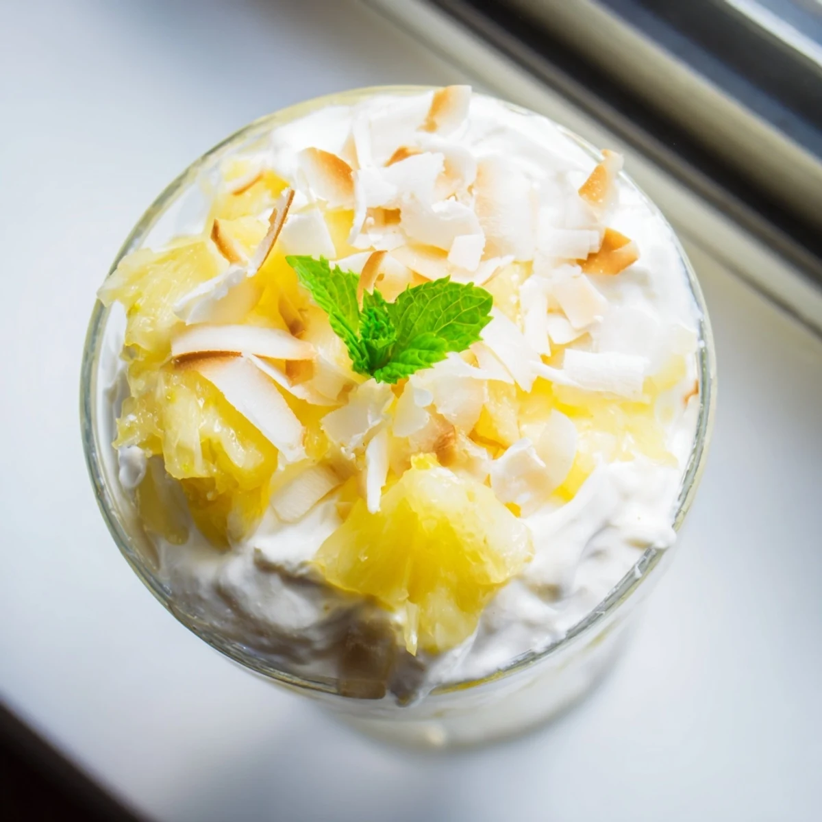 Creamy mini pineapple condensed coconut milk dessert served in elegant small glasses with mint garnish