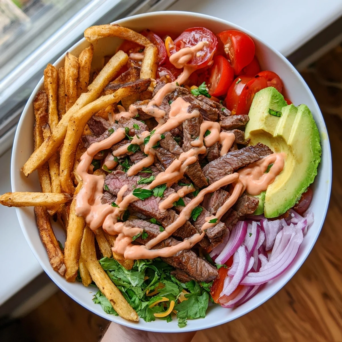 Juicy steak strips and crispy fries bowl drizzled with smoky zesty sauce