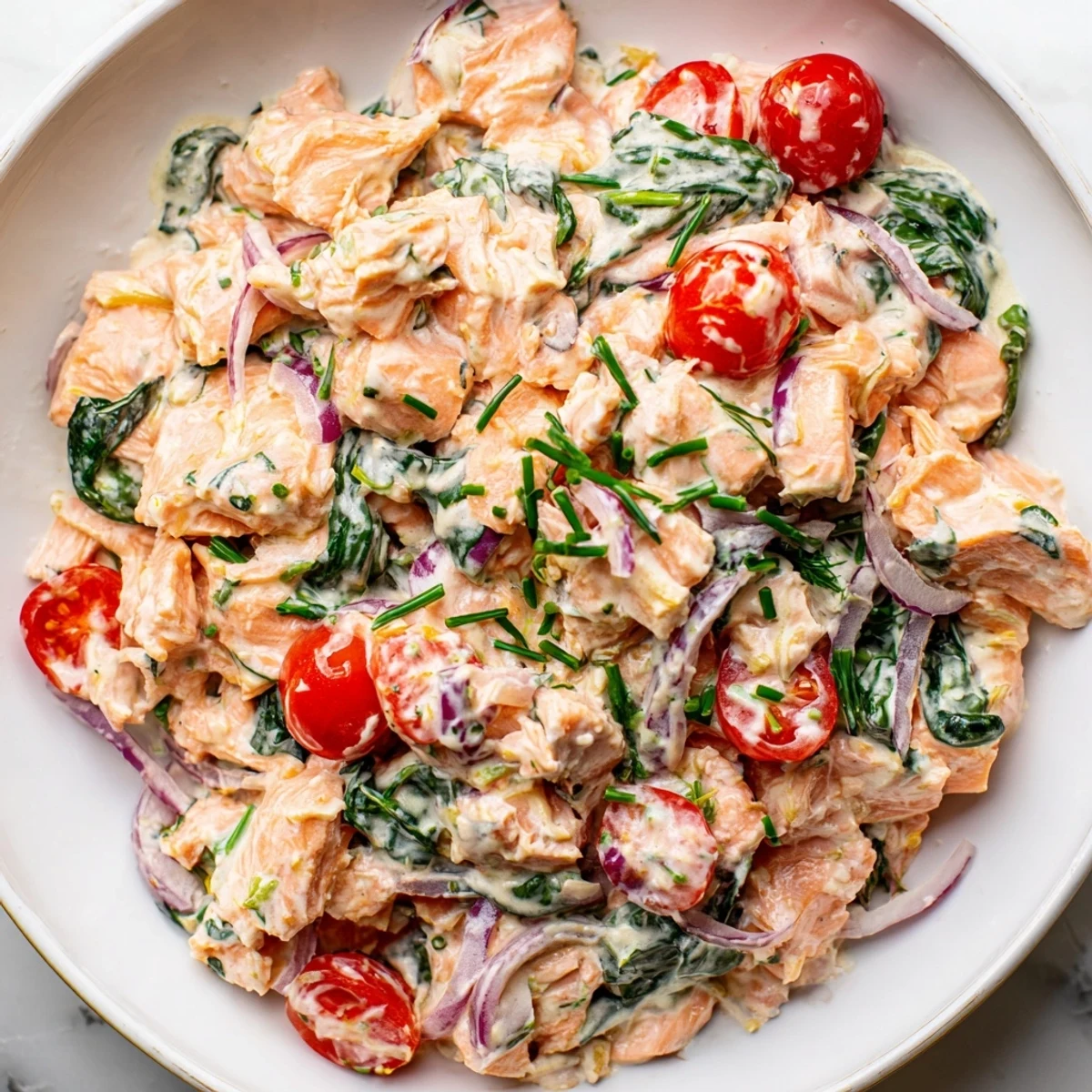 Creamy leftover salmon recipe served hot with wilted spinach and cherry tomatoes