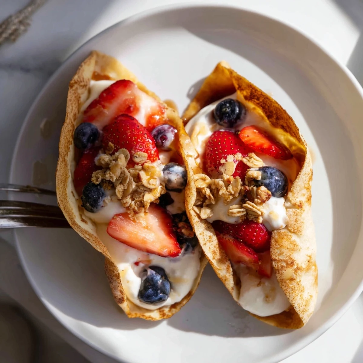 Fluffy pancake tacos filled with fresh strawberries and drizzled maple syrup on a white plate.