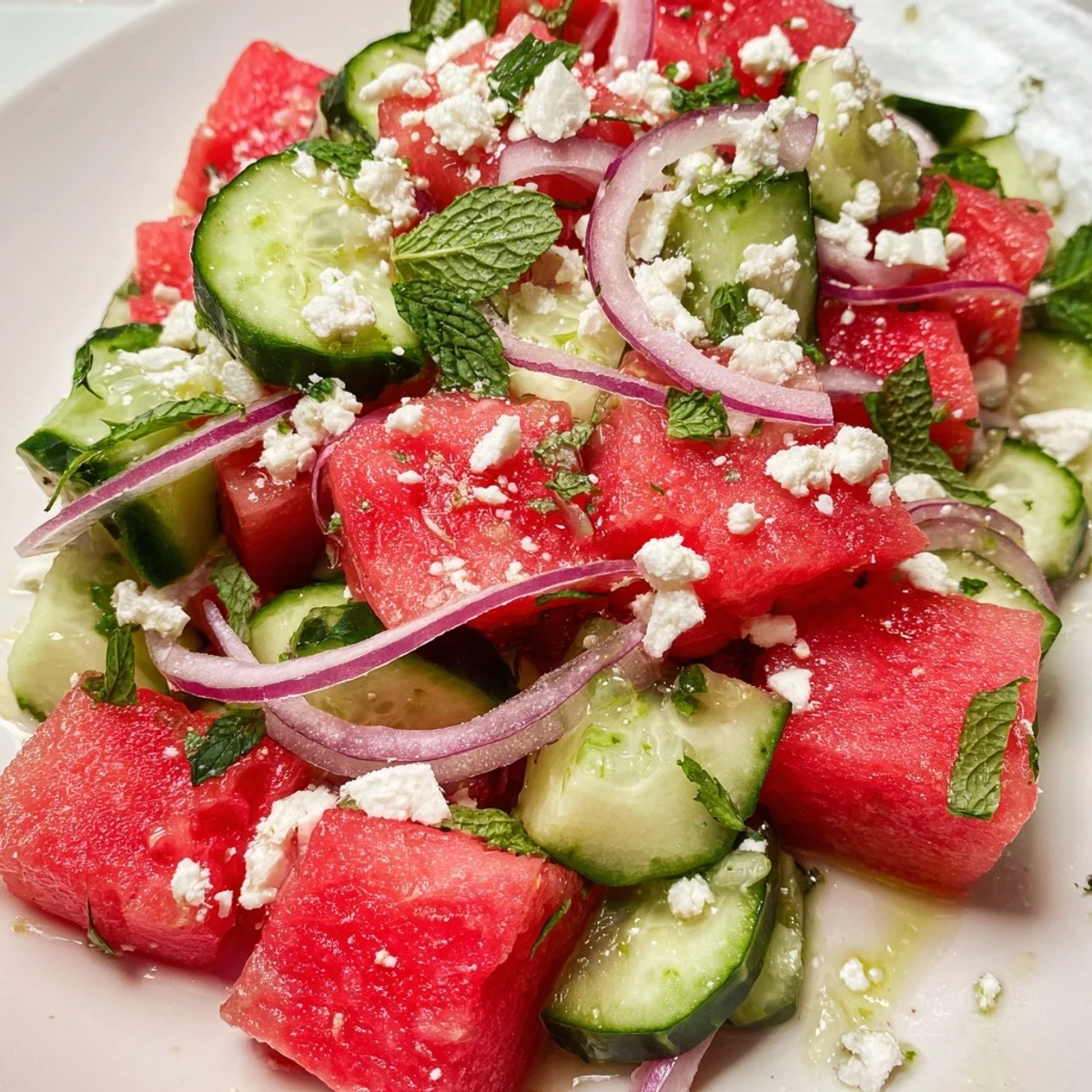 Juicy watermelon cucumber salad drizzled with tangy lime dressing and fresh mint leaves