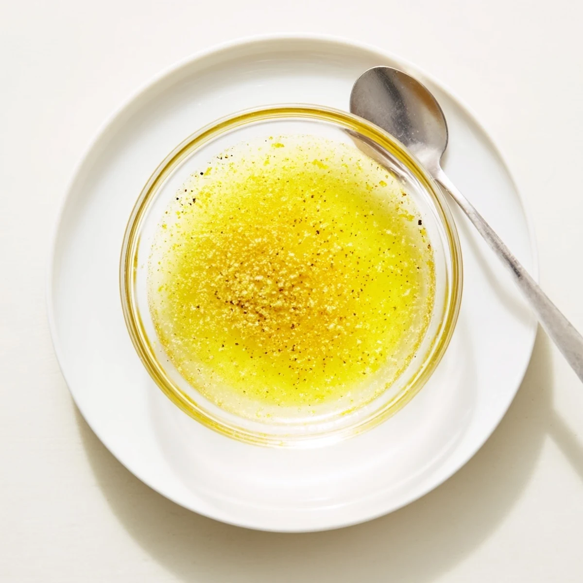 Golden lemon vinaigrette dressing recipe drizzled over fresh green salad leaves  
