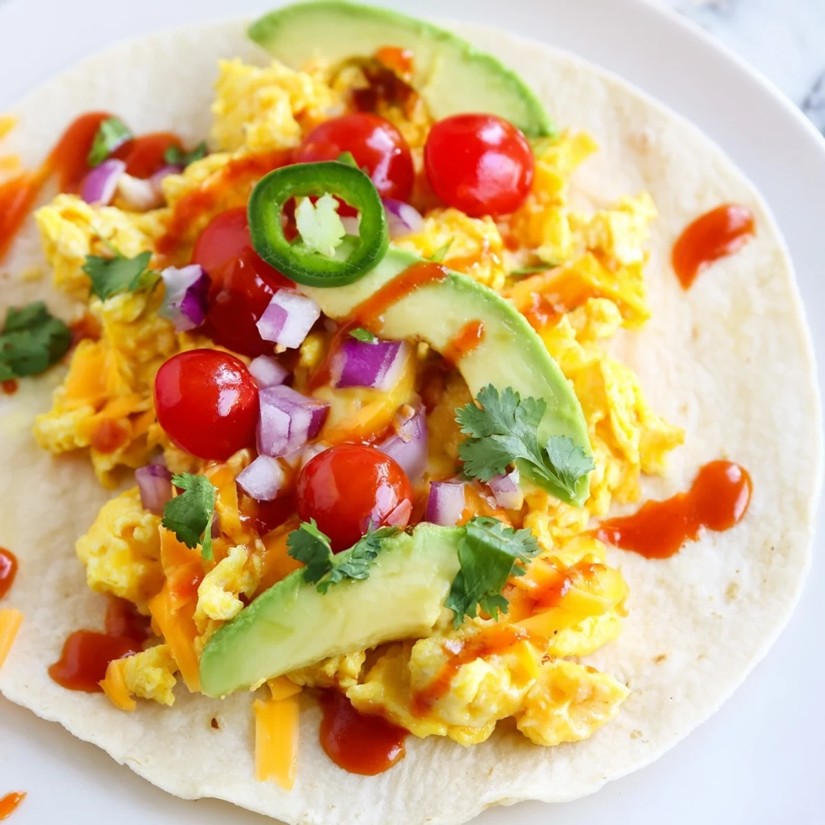 Delicious breakfast tacos recipe piled high with savory eggs, salsa, and melted cheddar cheese.